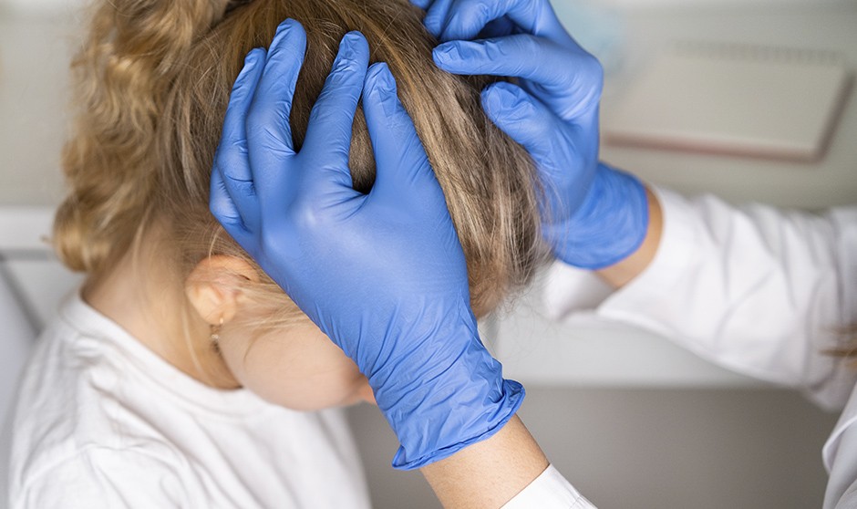 Un niño con piojos siendo examinado por un médico para emitir un justificante para el colegio