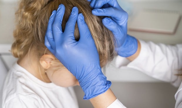 Un niño con piojos siendo examinado por un médico para emitir un justificante para el colegio