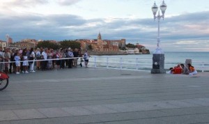 Un grupo de personas observan la intervención sanitaria en Gijón tras un cordón de seguridad.