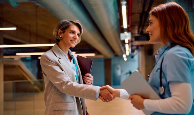 Dos profesionales sanitarias conversan en un entorno laboral moderno, reflejando la cercanía y atención personalizada de la oferta financiera de CBNK.