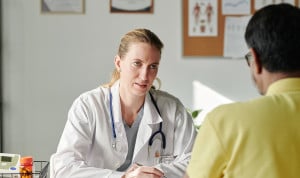  Una médica atiende a su paciente en consulta, con un traductor al lado