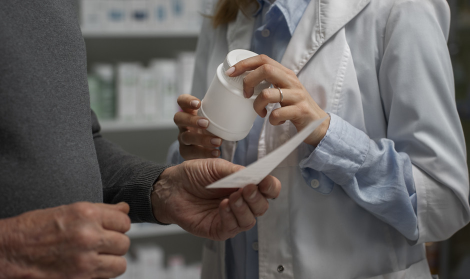 Una farmacéutica ofrece un medicamento a un paciente