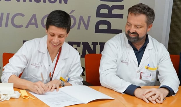 Una médico firma un documento ante la mirada de un colega