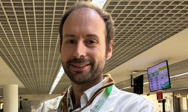 Un médico sonriente mira a cámara.