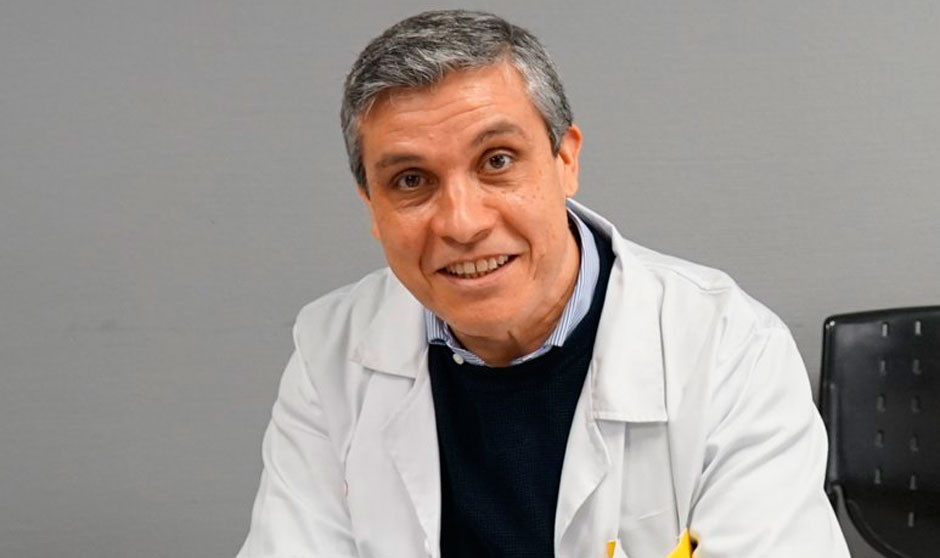 Médico posa a cámara sonriente con bata blanca