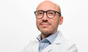 Médico con gafas y con bata posa mirando a cámara