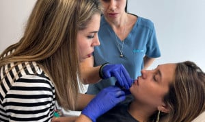 Docente de IFSES Estética instruye a una alumna en la técnica de infiltración labial con ácido hialurónico durante una práctica en consulta.