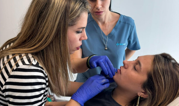 Docente de IFSES Estética instruye a una alumna en la técnica de infiltración labial con ácido hialurónico durante una práctica en consulta.
