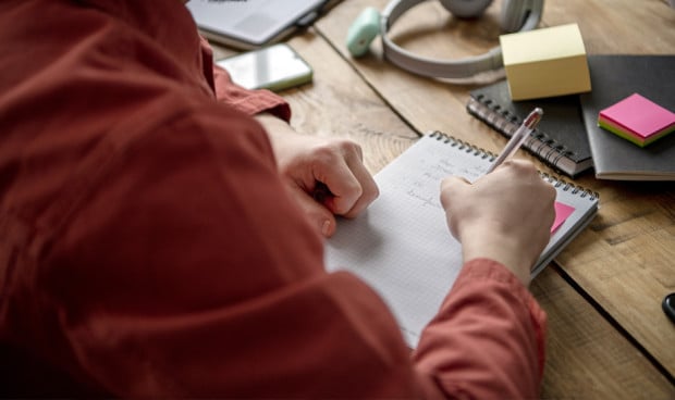 Estudiante tomando apuntes a mano, lo cual beneficia el rendimiento en Medicina