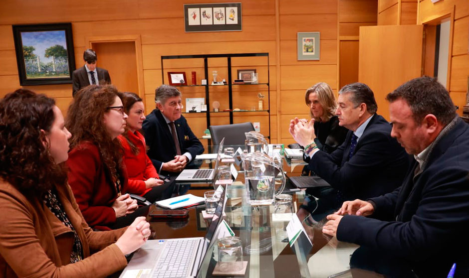 Imagen de una reunión de trabajo, con personas a ambos lados de una mesa, hablando