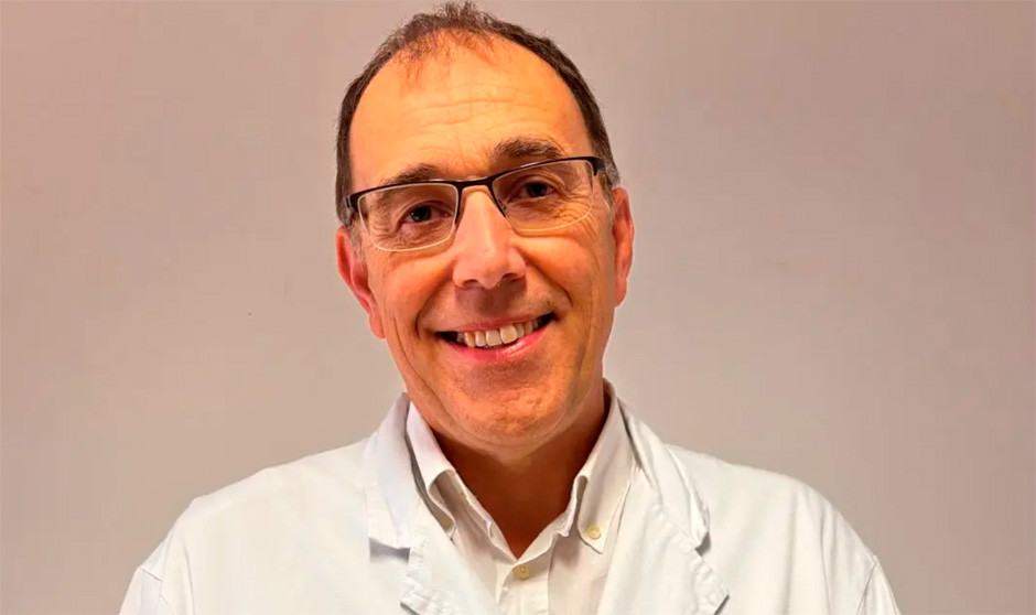 Un médico con bata blanca sonríe a cámara