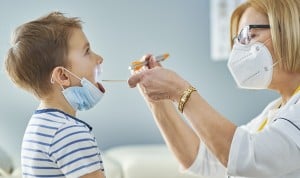 Una doctora observando la garganta de un niño.